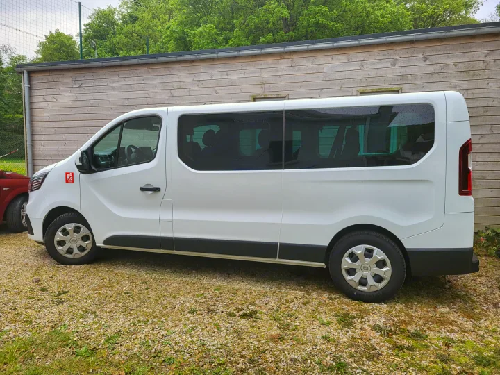White Renault passenger van, a versatile vehicle ideal for an RV rental fleet, parked by a wooden building.. RENAULT TRAFIC 2024