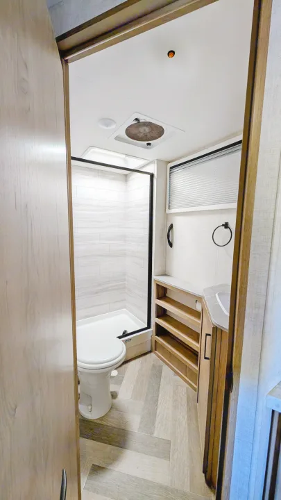 Compact RV rental bathroom with shower, toilet, and vanity, featuring modern finishes. Ideal for travel comfort.. Ember Overland 2023