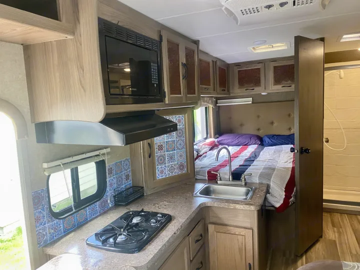 Spacious RV rental interior featuring a full kitchenette, cozy bed, and shower, perfect for your next road trip.. Forest River Coachmen Freelander 2017
