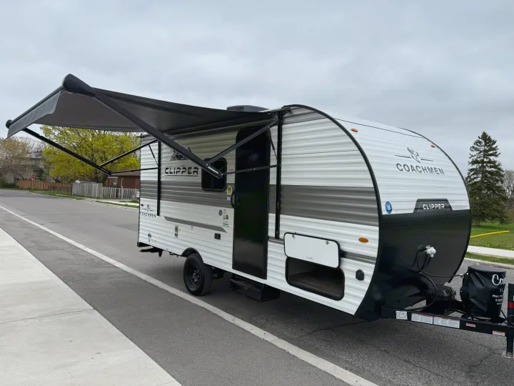 Coachmen Clipper RV rental: A white and gray travel trailer with its awning extended, parked on a street.. Coachmen Clipper 17CBH 2025