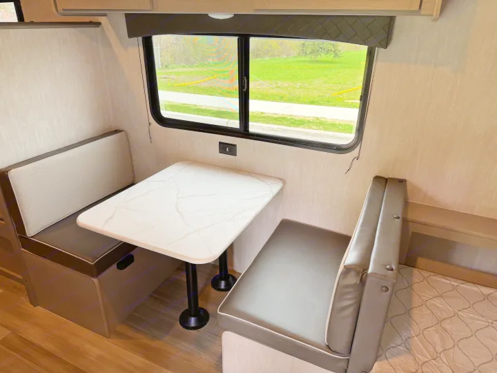RV rental: Cozy dinette features a white marble table, upholstered benches, and a window with a view of green space.. Coachmen Clipper 17CBH 2025