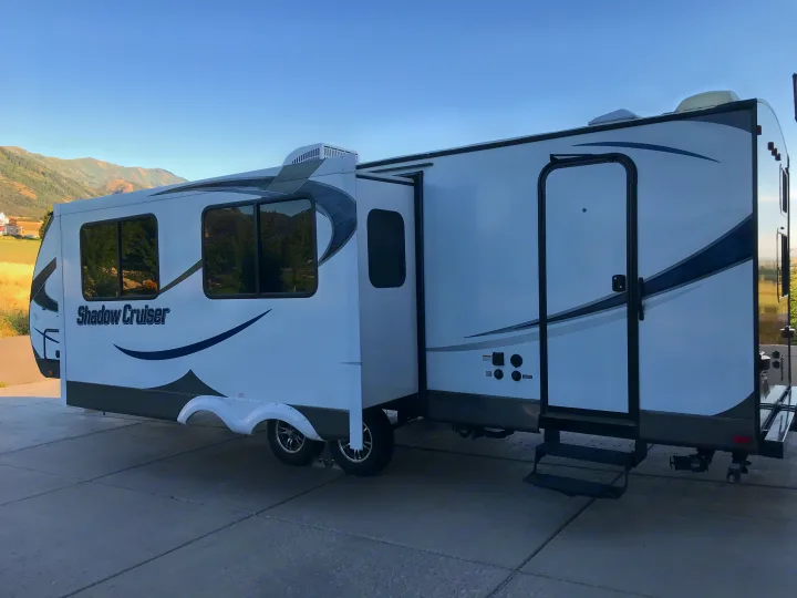 Spacious Shadow Cruiser travel trailer RV rental, with its slide-out extended, parked on pavement with mountains in background.. Cruiser RV Shadow Cruiser 2015