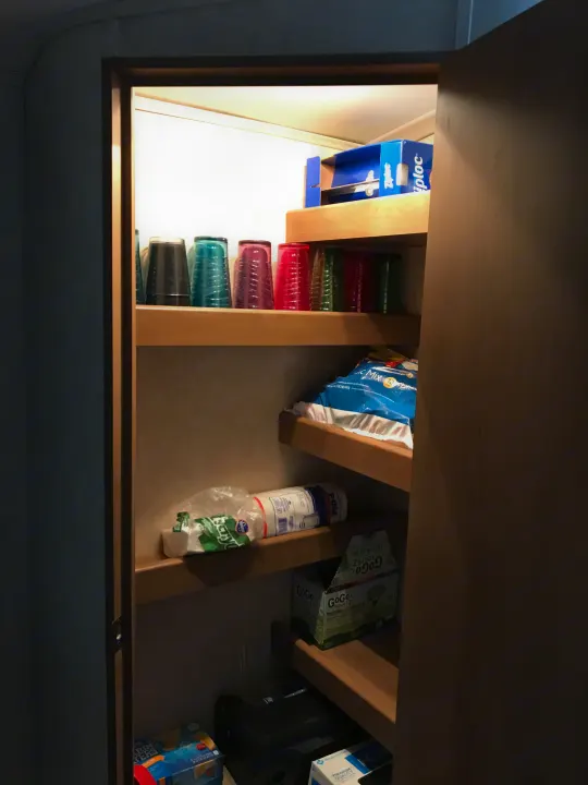 This RV rental pantry is efficiently organized, featuring shelves with cups, Ziploc bags, paper towels, and kid-friendly snacks.. Cruiser RV Shadow Cruiser 2015