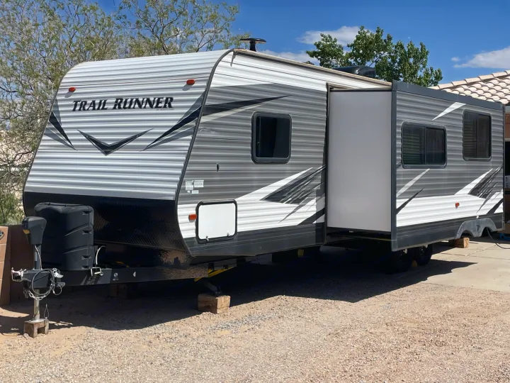This grey and white Trail Runner travel trailer is parked with its slide-out extended, perfect for an rv rental.. Heartland RVs Trail Runner 2019