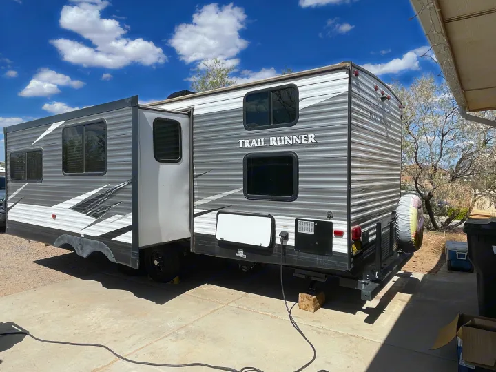 Spacious Trail Runner RV rental (travel trailer) with extended slide-out, parked on concrete under blue sky.. Heartland RVs Trail Runner 2019