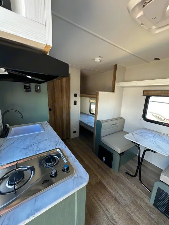 Modern RV rental interior featuring an efficient kitchen, dinette, and bunk beds. Ideal for travel adventures.. Heartland Eddie Bauer 2025