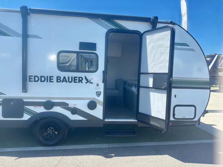 White Eddie Bauer travel trailer with open door, showing interior bunk. Ideal for your next RV rental adventure.. Heartland Eddie Bauer 2025
