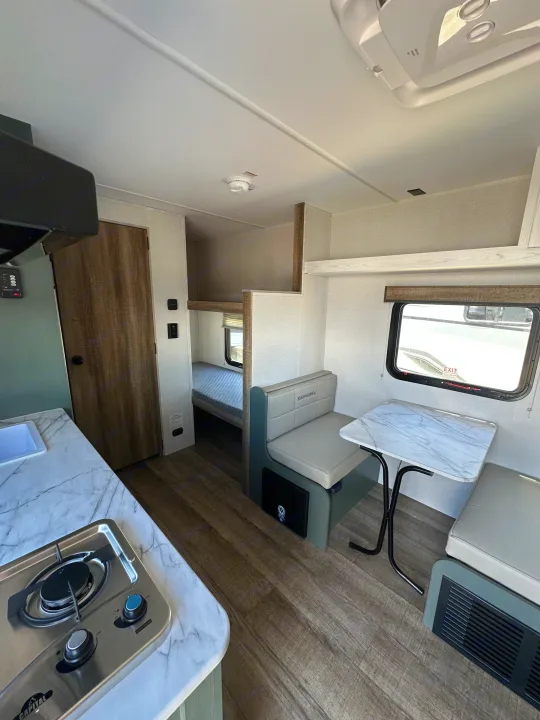 Modern RV rental interior: kitchen (stove, marble counter), Eddie Bauer dining booth, and bunk beds. Perfect for camper travel.. Heartland Eddie Bauer 2025