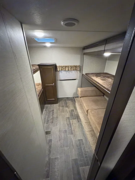 Step inside this RV rental, showcasing bunk beds, a wardrobe, and versatile sofa seating for comfortable travels.. Keystone RV Bullet Ultra Lite 2019