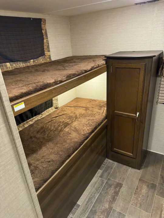 RV rental: Cozy brown bunk beds and storage cabinet on textured gray tile-look flooring.. Keystone RV Bullet Ultra Lite 2019