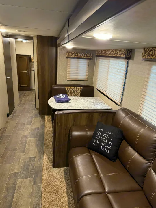 RV rental interior with a modern dining booth, comfy brown sofa, and hallway. A spacious and cozy camper living space.. Keystone RV Bullet Ultra Lite 2019