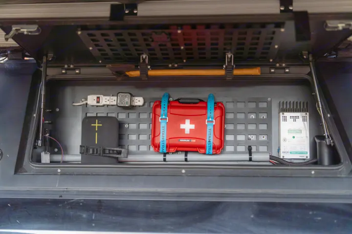 Optimized RV rental storage: a neatly organized compartment with first aid, electronics, axe, and solar charge controller.. Ford Ford F150 2020