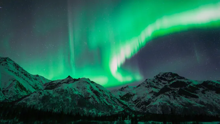 Aurora borealis brilliantly illuminates snow-capped mountains and starry skies, ideal for an RV rental journey.. Ford Ford F150 2020