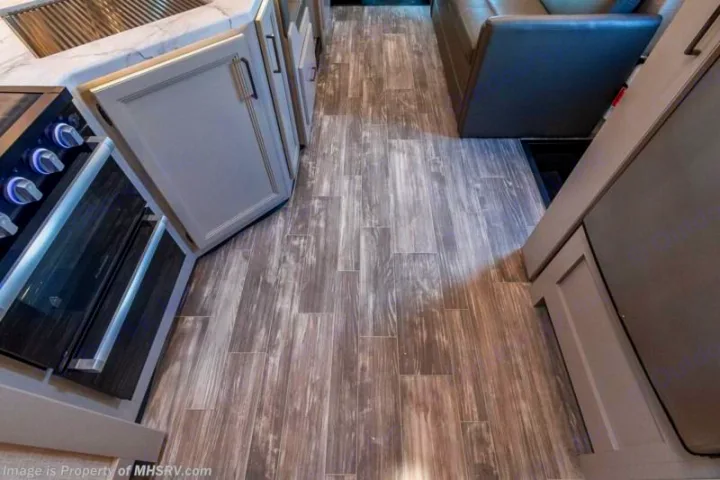 RV rental interior: Modern kitchen cabinetry, distressed wood-look flooring, and living area with a dark sofa. Spacious and inviting.. Thor Motor coach Geneva 2025