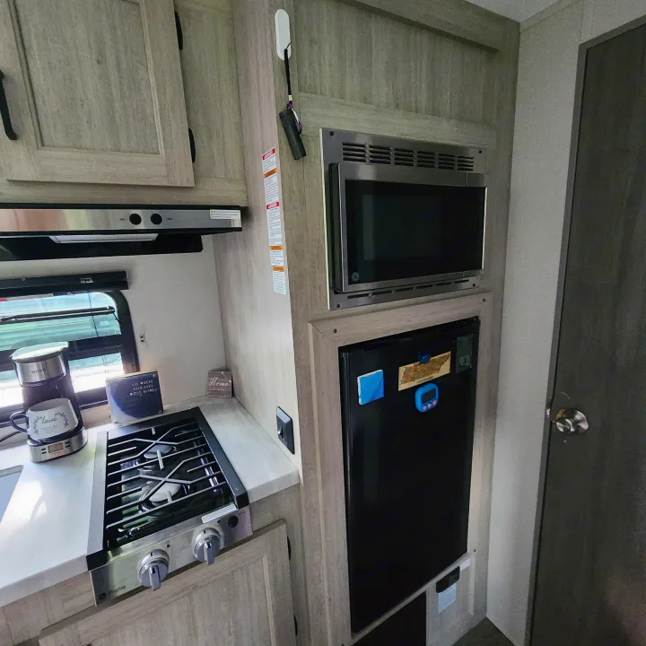 RV rental kitchen: This cozy interior features a microwave, stove, fridge, and coffee maker, perfect for your travels.. Coachmen Catalina 2024