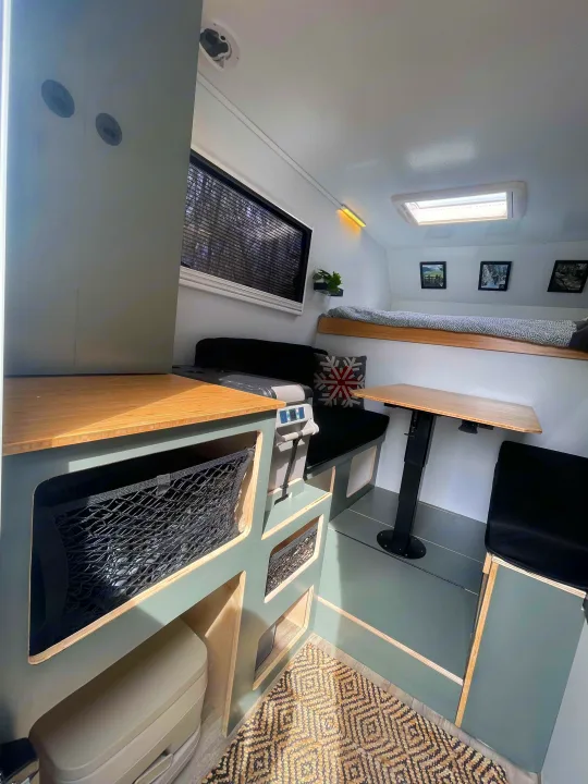 Bright RV rental interior: cozy bunk bed, dining space with adjustable table, compact kitchen counter, and integrated storage nets.. Ford Lightning 2024