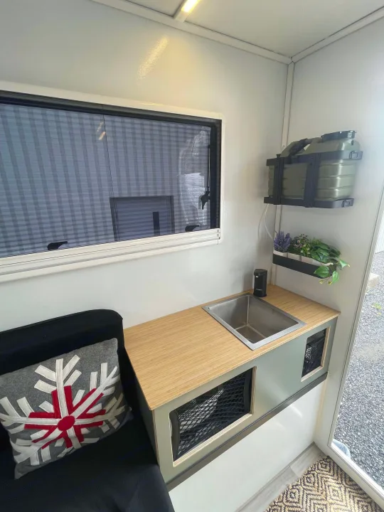 Compact RV rental interior featuring a kitchenette with sink, storage, window, cozy seating, and wall-mounted jerry can.. Ford Lightning 2024