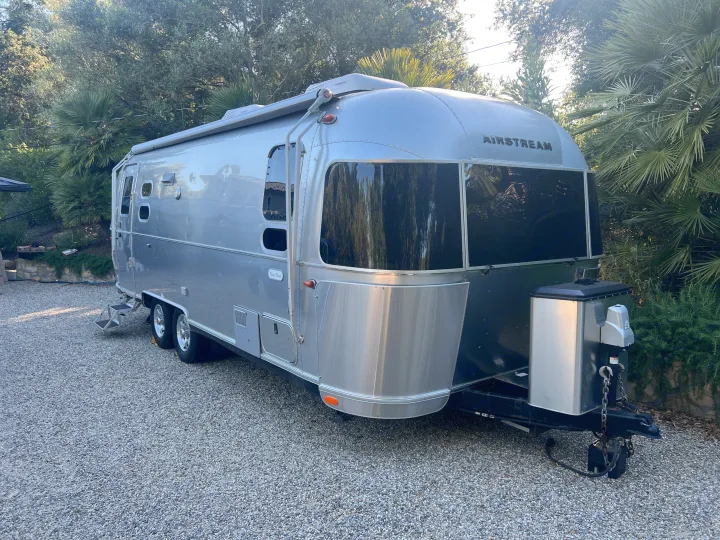 Sleek Airstream travel trailer on gravel, ideal for RV rental. Perfect for a luxurious camping vacation.. Airstream Flying Cloud