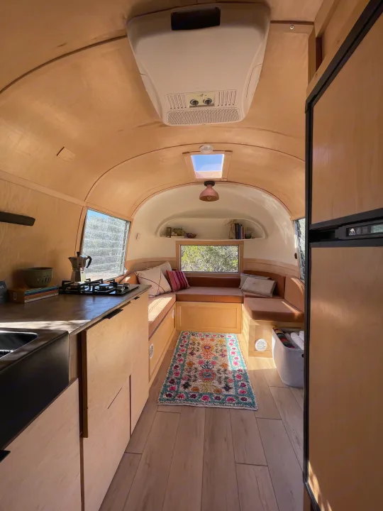 Inviting RV rental interior: a bright, wood-lined space featuring a compact kitchen, comfy dinette, and skylight.. Airstream Safari 1964