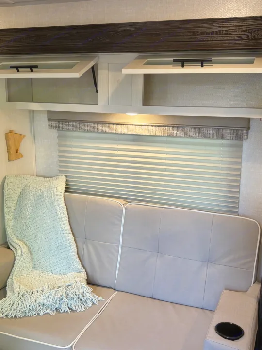 Cozy RV rental interior: sofa with blanket, window blinds, and open cabinets. Ready for your next trip!. Forest River R-Pod 2022