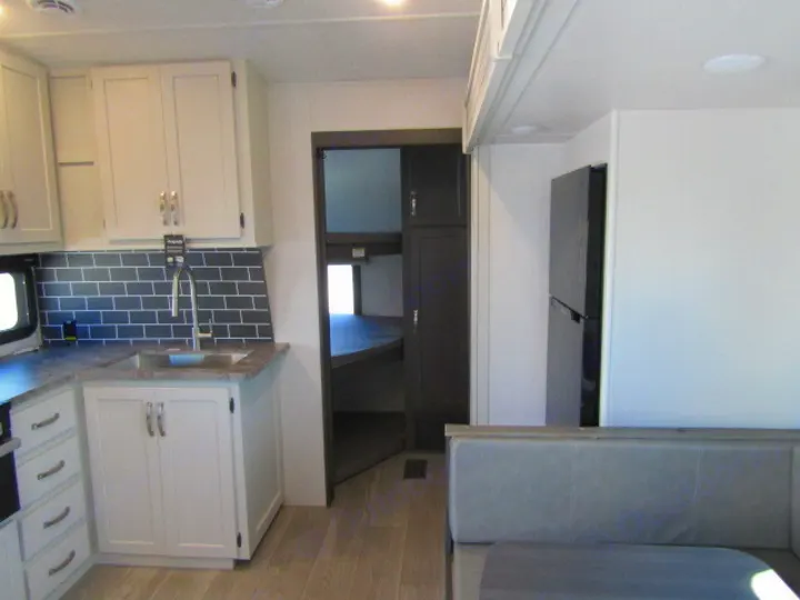 Spacious RV rental interior showcasing a modern kitchen with dark subway tile, fridge, and bunk beds.. Keystone Cougar 2025
