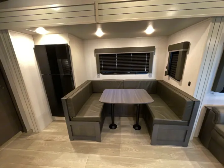 This inviting RV rental interior showcases a gray dinette booth, table, and a black refrigerator for your next trip.. Keystone Cougar 2025