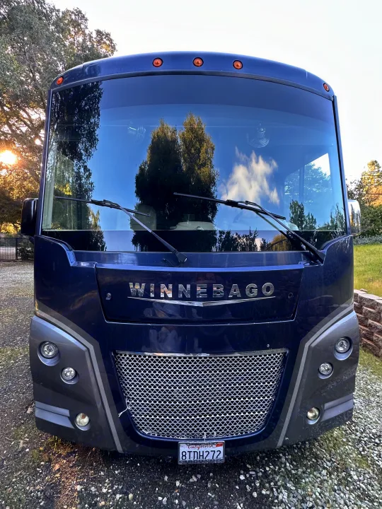 Front of a blue Winnebago motorhome, ideal for an RV rental adventure, parked on gravel.. Winnebago Adventurer 2021