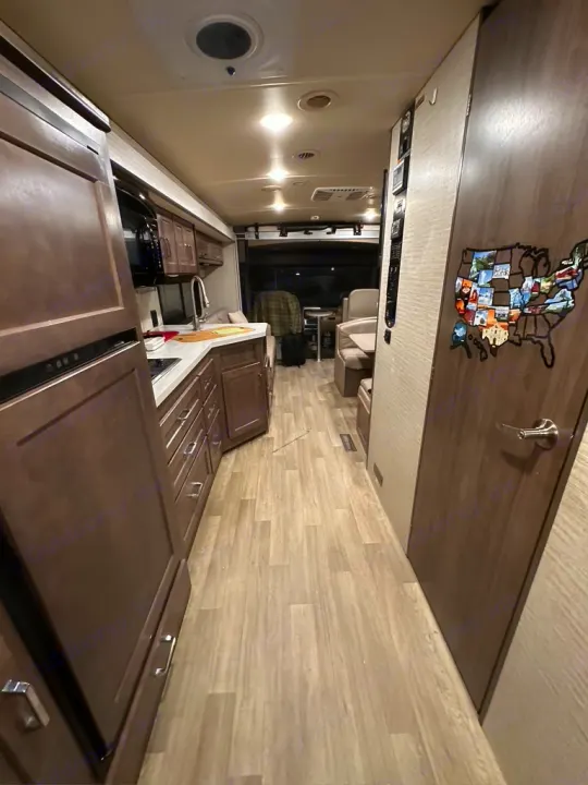 RV rental: Bright interior with full kitchen, US map decor, and ample living space. Light wood flooring throughout.. Winnebago Adventurer 2021