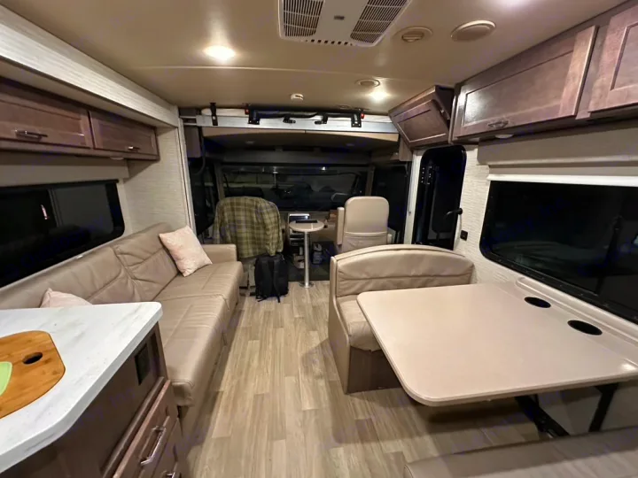 Spacious RV rental interior featuring a comfy sofa, dining area, and kitchen counter. Ready for your next adventure!. Winnebago Adventurer 2021