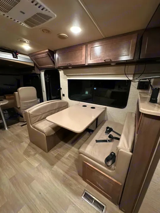 Discover the comfortable interior of this RV rental, featuring a dinette with benches, a table, and ample overhead storage.. Winnebago Adventurer 2021