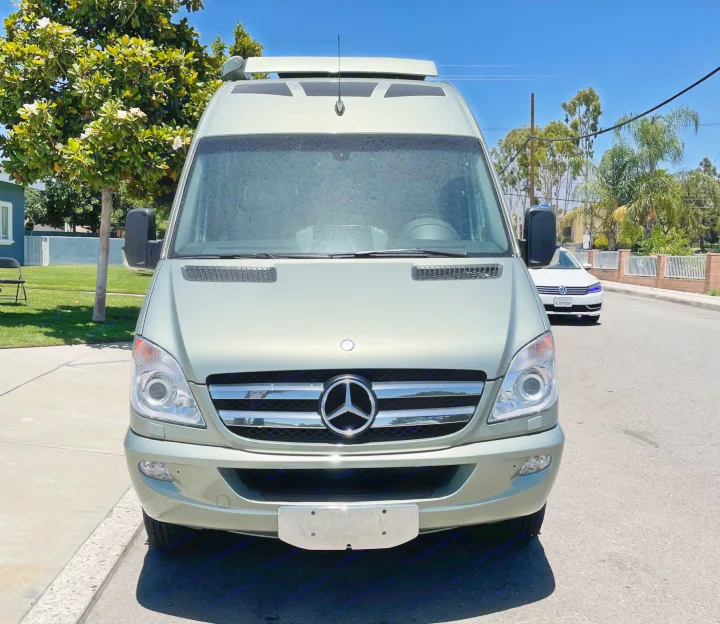 Front view of a light green Mercedes-Benz Sprinter camper van, an excellent RV rental option parked on a sunny street.. Roadtrek Roadtrek Class B 2013