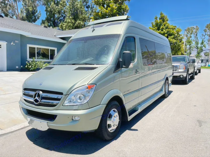A light green Mercedes-Benz Sprinter RV rental van, parked on a sunny street with other vehicles visible behind it.. Roadtrek Roadtrek Class B 2013
