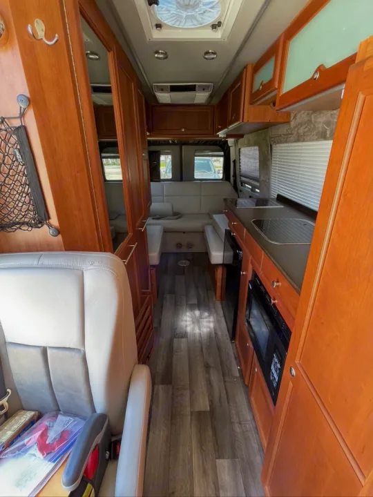 Inside this rv rental: a cozy interior with light wood cabinets, kitchen, and rear lounge area.. Roadtrek Roadtrek Class B 2013