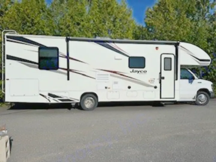 A large white Jayco Class C RV rental, perfect for road trips and outdoor adventures, parked on asphalt.. Jayco Redhawk 2019
