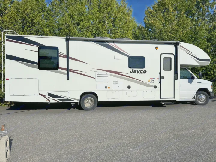 White Jayco Redhawk Class C motorhome, ideal for rv rental travel. Features sleek stripes, windows, and outdoor storage bays.. Jayco Redhawk 2019