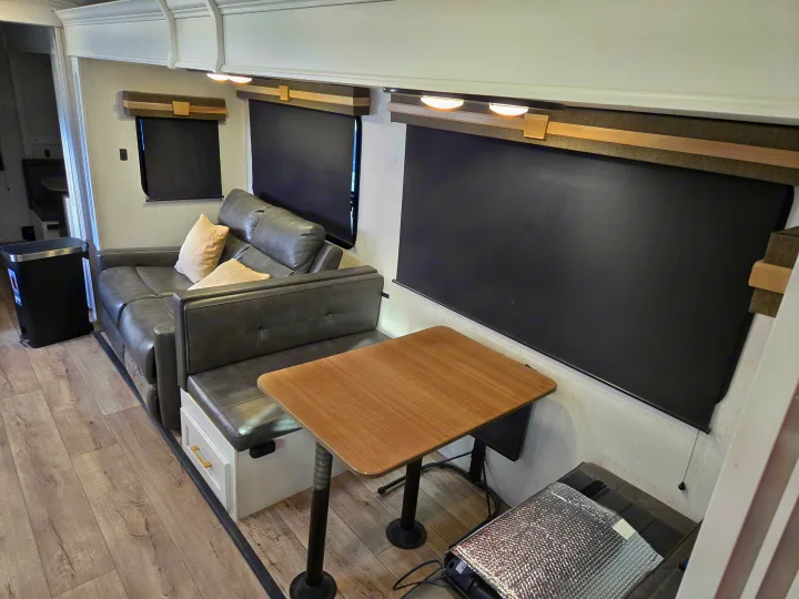 Modern RV rental interior with dinette seating, a table, and dark window shades for privacy.. Dutchman Astroia 2022