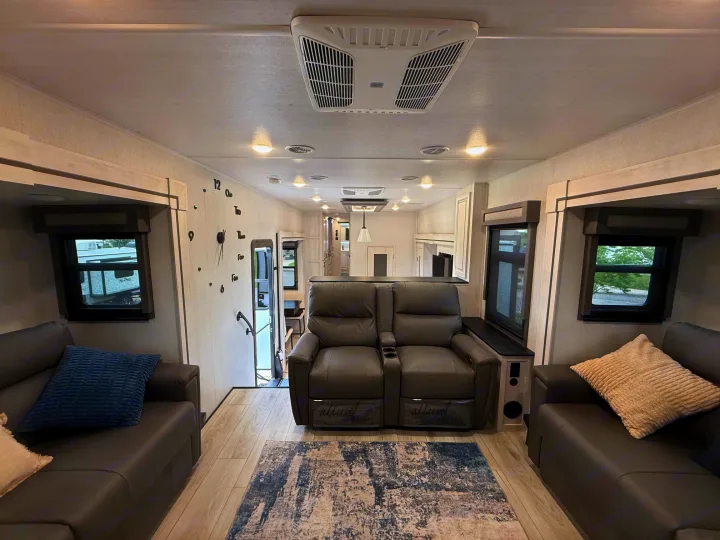 RV rental: inviting interior living space with plush recliners, sofa, light wood-look floor & bright lights.. East to West Ahara 2024