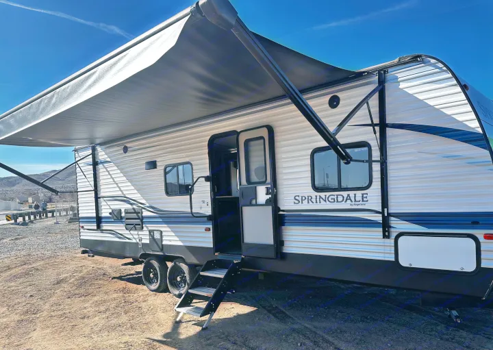 Explore with this Springdale travel trailer RV rental, parked with its awning extended and steps down, inviting adventure.. Keystone RV Springdale 2021