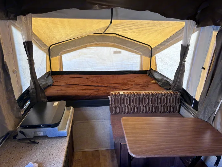 Spacious pop-up camper interior with a cozy bed, dining table, and kitchen counter. Ideal for your next RV rental.. Palomino Other 2017