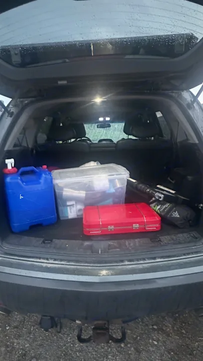 View inside a vehicle's trunk, packed for an RV rental trip. Shows a blue water jug, clear bin, and outdoor gear.. Other Other 2007