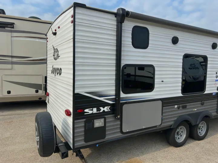 White & gray Jayco SLX travel trailer (RV rental option) with a rear spare tire, side windows, and an awning.. Jayco 264Bunk House 2022