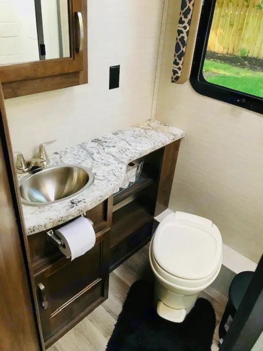 Enjoy this compact RV rental bathroom featuring a stainless steel sink, granite-look counter, toilet, and window view.. Jayco Redhawk 2018