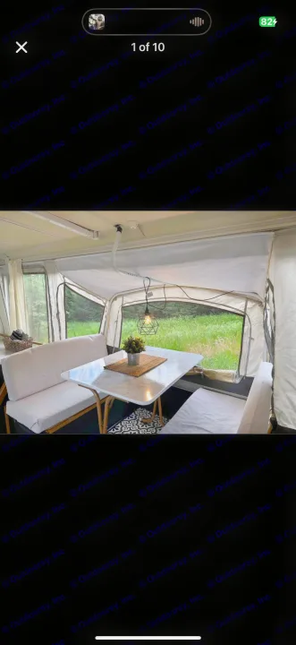Cozy RV rental dinette setup with white cushions, a modern light, and views of lush nature. Perfect for camping.. Coleman Grand Tour 2002