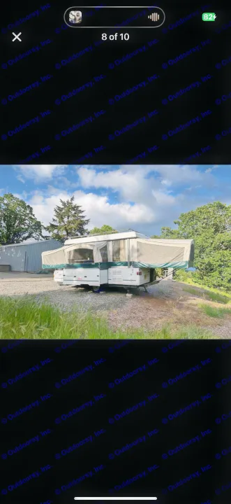 Pop-up RV rental ready for outdoor adventure! This camper is set up on a gravel patch amidst trees, perfect for camping.. Coleman Grand Tour 2002
