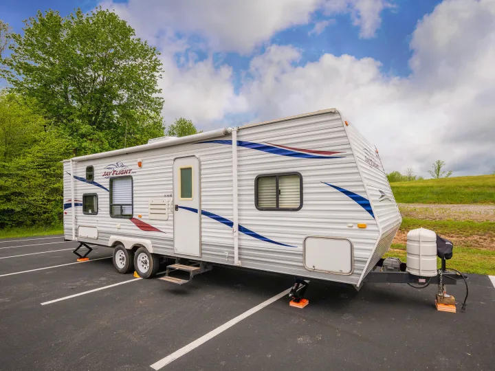 Jay Flight travel trailer RV rental parked on asphalt under blue skies, ready for your next adventure in nature.. Jayco Jay Flight 2010
