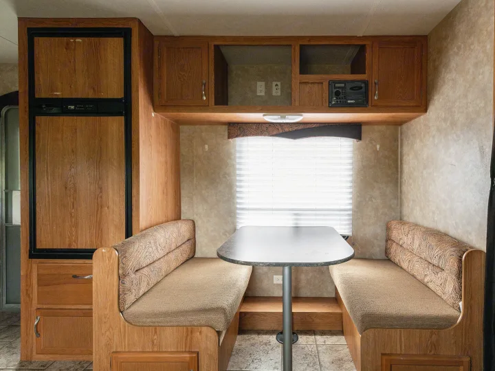 Interior of an RV rental showing a dinette, overhead cabinets, and a built-in refrigerator.. Jayco Jay Flight 2010