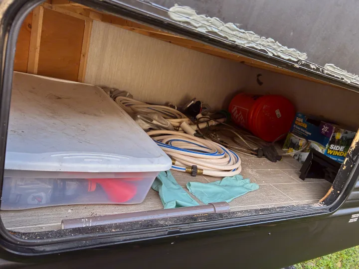 This RV rental storage bay is packed with essential gear: water hoses, sewer support, and accessories for travel.. Forest River Cherokee Grey Wolf 2020