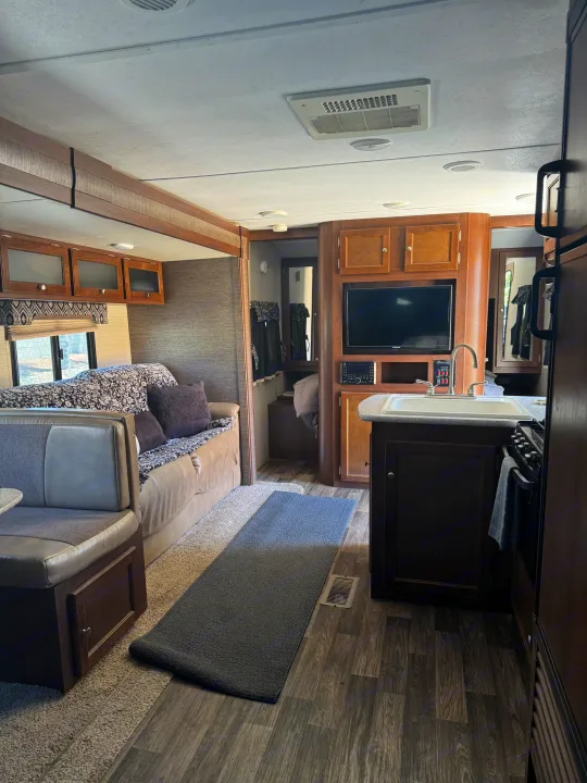 This RV rental interior features a cozy living space with a dinette, sofa, and a compact kitchen with a sink and stove.. Keystone RV Bullet Ultra Lite 2017