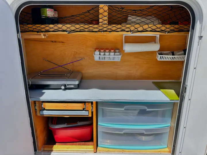 Compact, organized RV rental kitchen setup with stove, spices, and smart storage for camping adventures.. Hiker Deluxe 2018