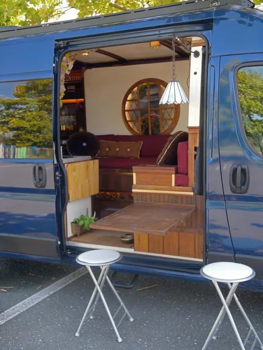 Cozy RV rental van conversion with charming interior, round window, pull-out table & stools. Ideal for mobile living.. Dodge Ram Promaster 3500 2023